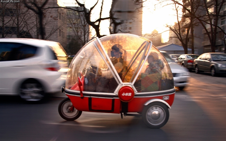 beijing_china_-_a_woman_and_her_son_sit_in_the_capsule_of_an_electric_tricycle_as_they_drive_along_a_main_road.jpg